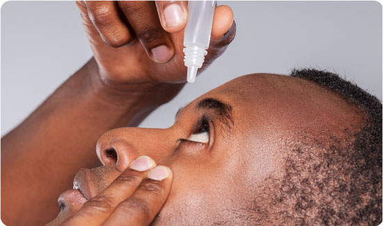 A man dropping eye wash solution in eye