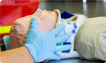 First Aid Trainer applying an ambu collar to training dummy's neck