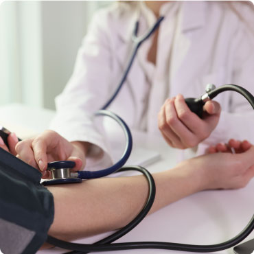 Doctor using a sphygomanometer to test a patients blood pressure. The doctor is using a stethoscope on the patients forearm
