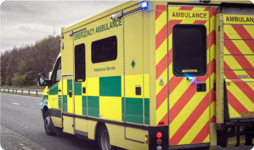 Ambulance driving fast on a road with its emergency lights on