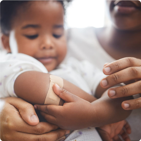 Mother applying a bandaid to her daughters arm at home