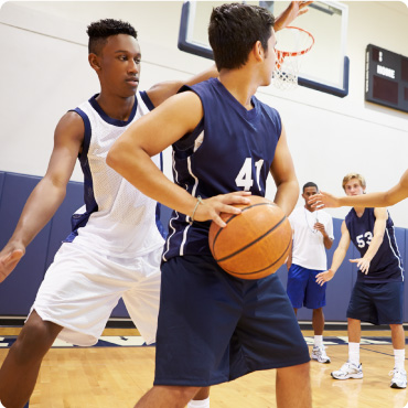 Teenage boys playing basketball on an indoor court