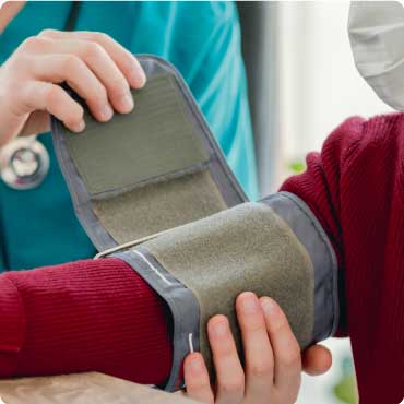 Doctor putting a blood pressure monitor cuff on a patient