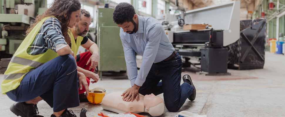 Male instructor showing first medical aid on doll during training course indoors