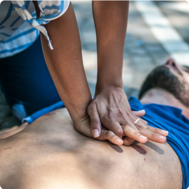 Someone performing CPR on a man lay on a road