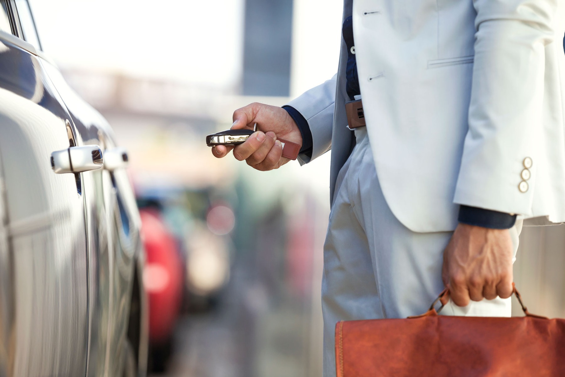 Businessman with briefcase unlocking his car, close up