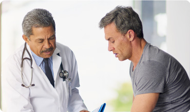 Doctor with cardiology stethoscope around his neck talking to a patient who looks worried