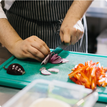 Chef chopping vegetables on a blue chopping board