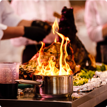 Chef preparing food in a pan with fire