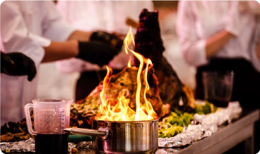 Chef preparing food in a pan with fire