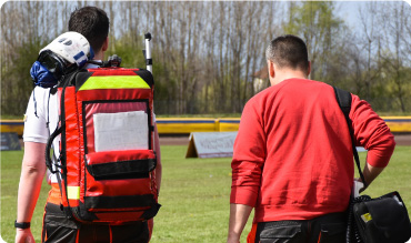 First responders carrying first aid equipment onto a sports pitch