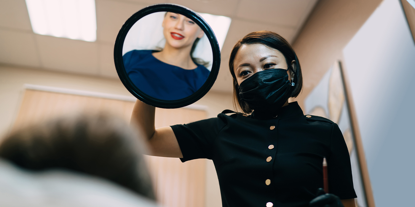 Girl looking at lips in mirror near beautician