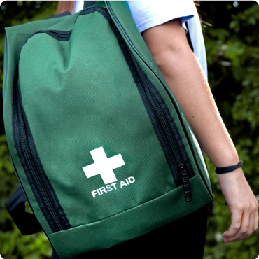 A woman with the Green First Aid Rucksack on her shoulder