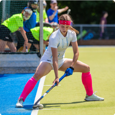 Panoramic image of confident female field hockey player performing short corner