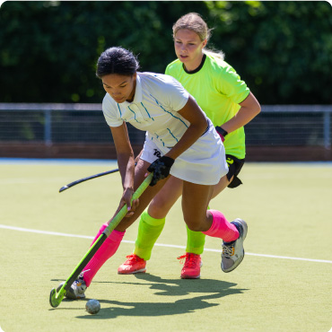 Two female field hockey players fighting for the hockey ball on the pitch