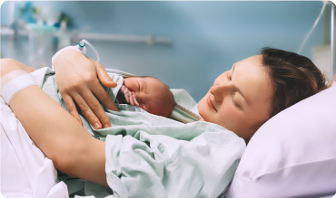 Young mother hugging her newborn baby after delivery.