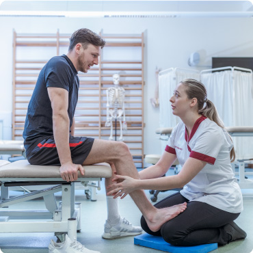 Physiotherapist checking on an athletes leg in a clinical environment