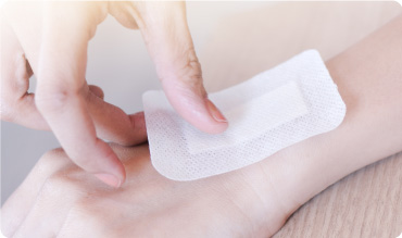 Girl putting a wound dressing on her wrist