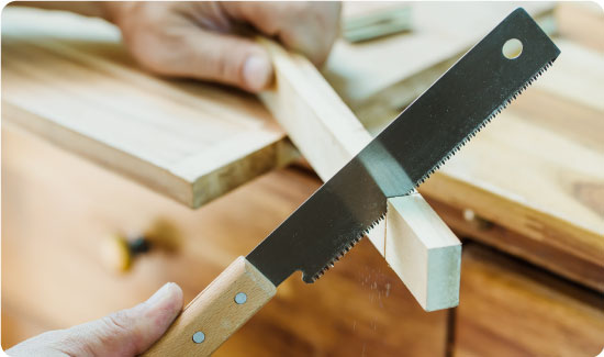 Someone sawing a piece of wood