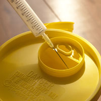 Someone putting a needle in a sharps bin