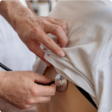 Doctor examining the back of a patients chest with a stethoscope