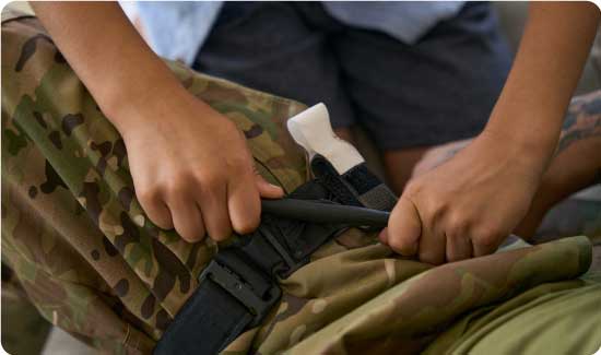 Applying tourniquet to soldier's leg