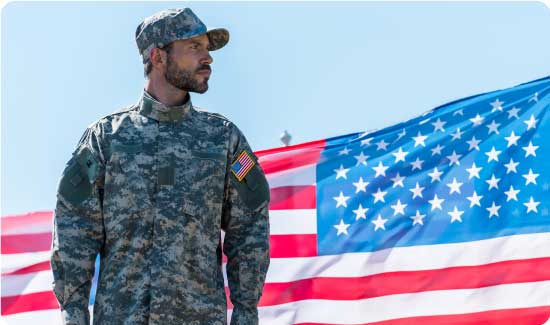 soldier in uniform standing near american flags against blue sky