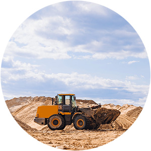 A construction vehicle moving dirt at a construction site under a partly cloudy sky
