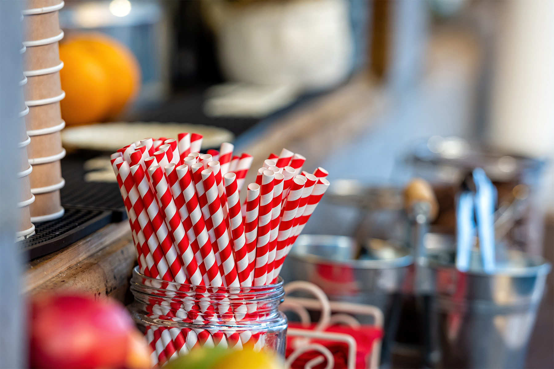 drink straws, various accessories and a stack of paper cups in a street cafe