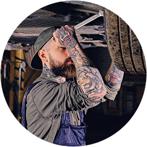 Tattooed mechanic working under a vehicle in a workshop