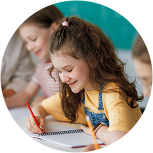 Smiling young girl writing in a notebook in a classroom