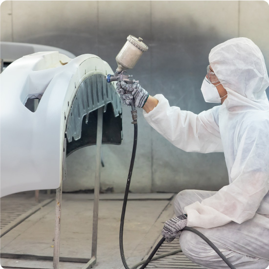 Person spray painting with face mask on