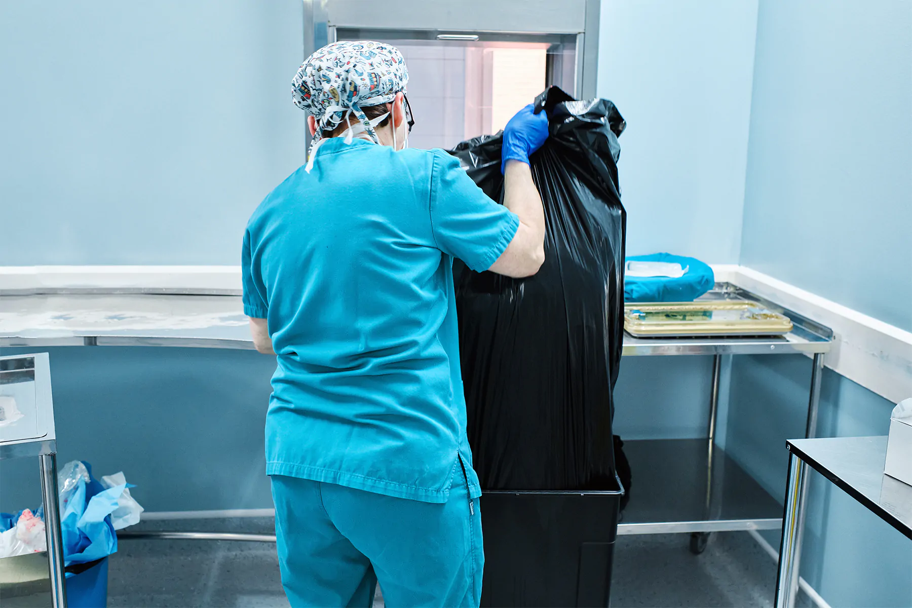 woman health workers remove a bag of garbage at a hospital
